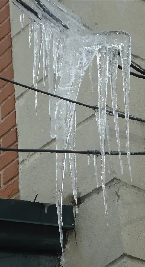 Icicles hanging from wires beside a building