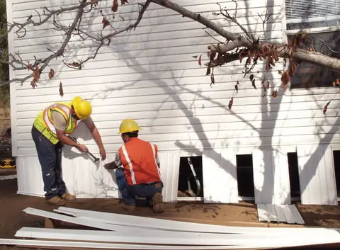 Workers installing skirting around the base of a manufactured home