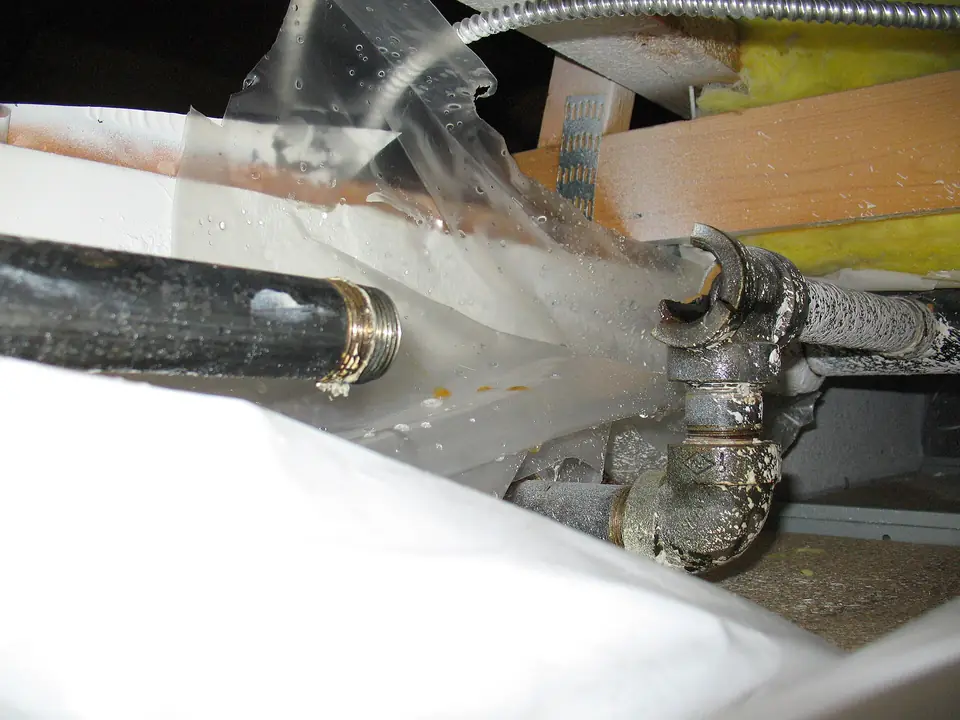 Water spraying from a steel pipe fitting that has split open